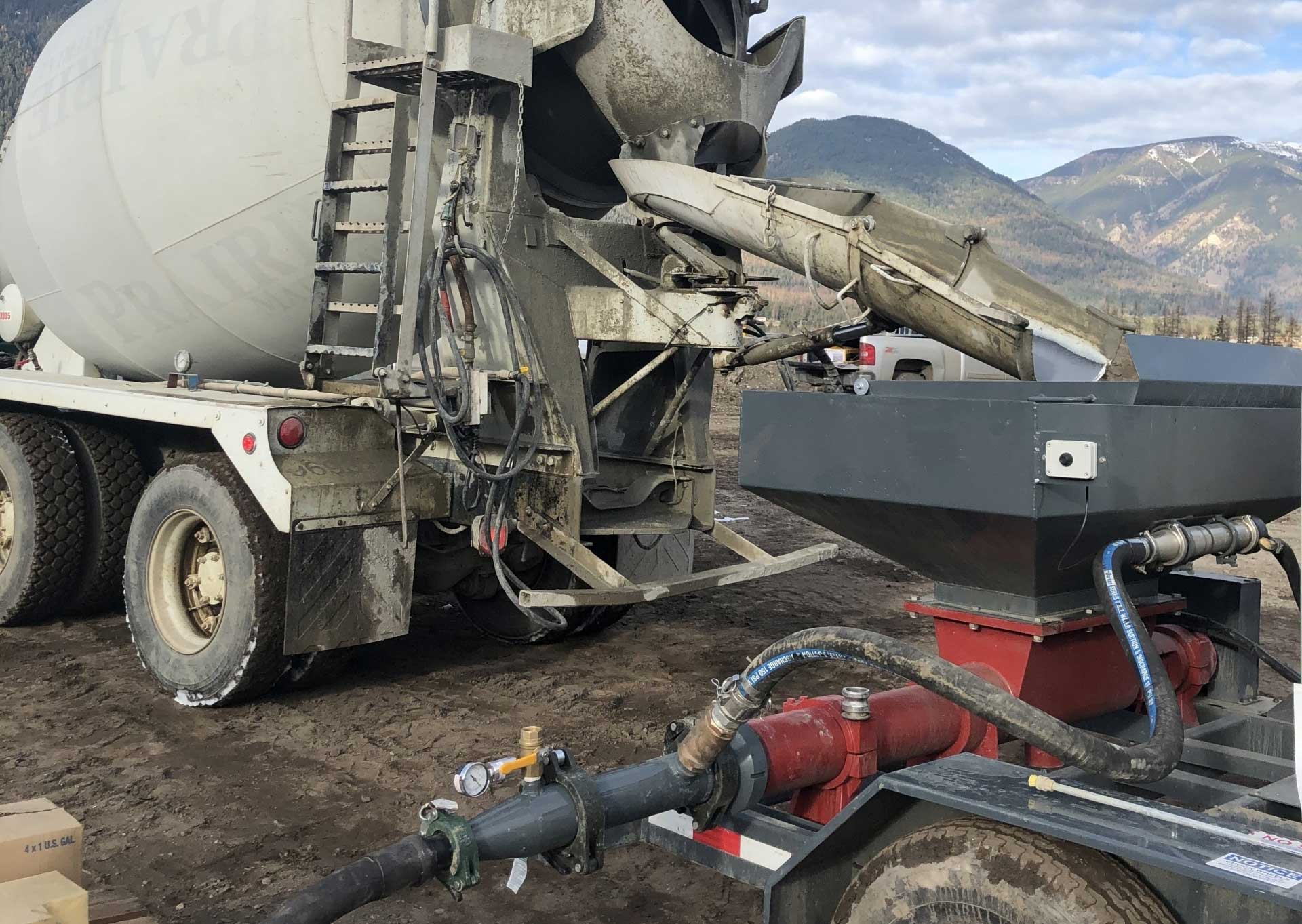 Cement truck pouring concrete into large punmp at the Blue tubing at the Komatsu Manufacturing Plant